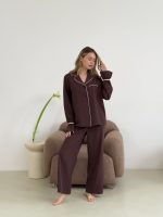 Жінка в коричневій піжамі сидить на кріслі